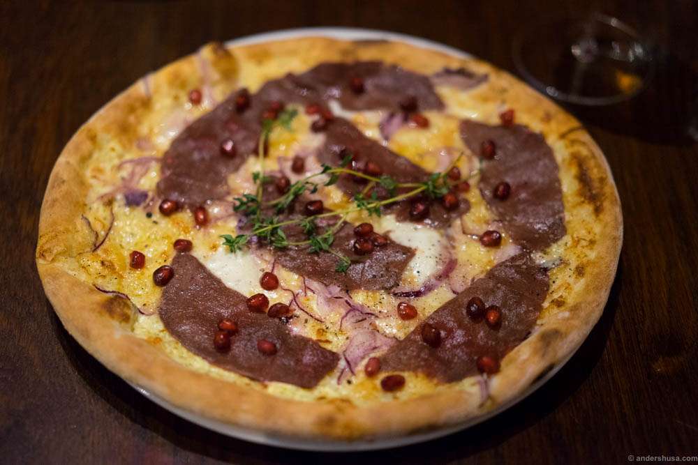 White pizza with carpaccio of reeindeer from Røros, with pomegranate and red onion.