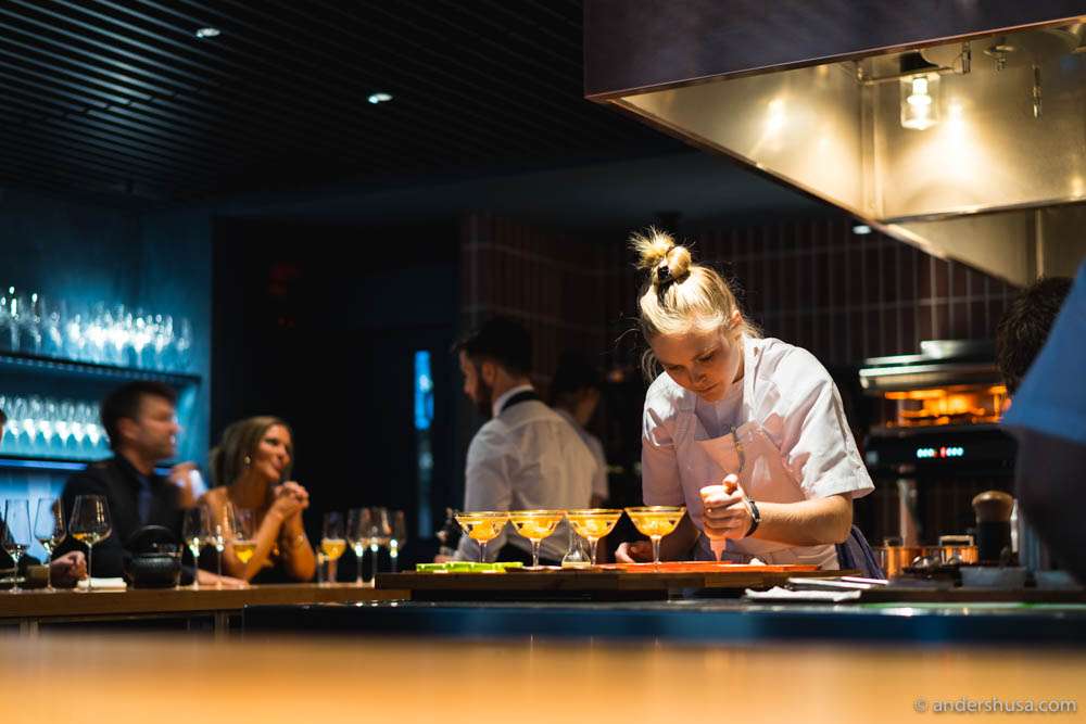 More than half of the 23 guests are seated around the bar facing the open kitchen