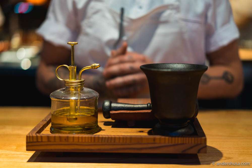 Cold-pressed rapeseed oil and a mortar & pestle with herbs inside