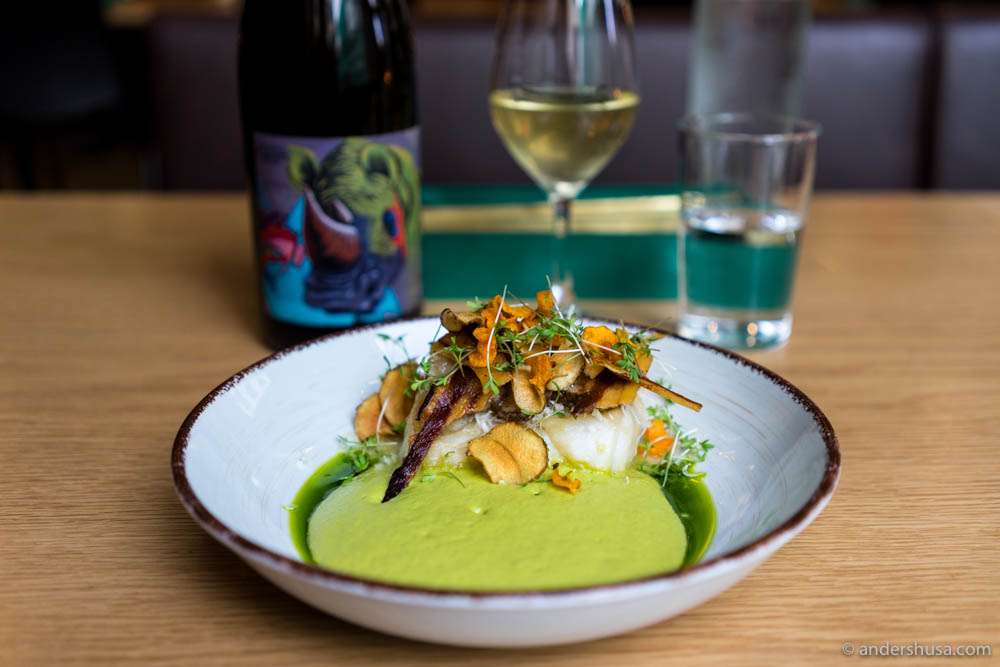 Stockfish poached in white wine, with peas espuma, leek oil, and chips of Jerusalem artichoke, carrots & bacon