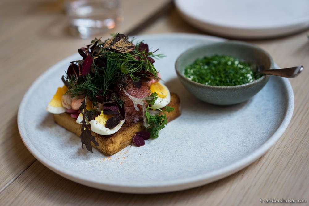 Lumpfish roe with eggs, hand-peeled shrimps, and kohlrabi served on a slice of fried brioche bread with a sauce on the side of crème fraîche and chives