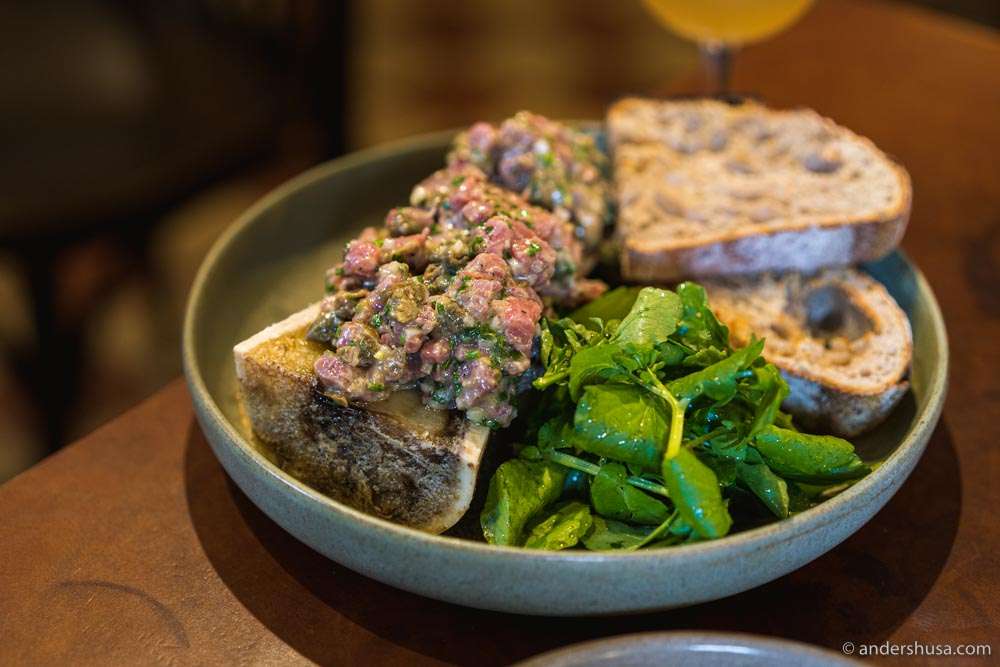 Baked bone marrow with beef tartare, mustard, and cress.